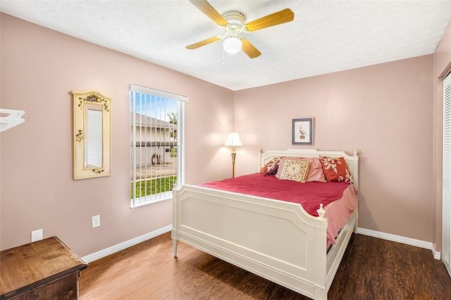 bedroom with a textured ceiling, ceiling fan, wood finished floors, and baseboards