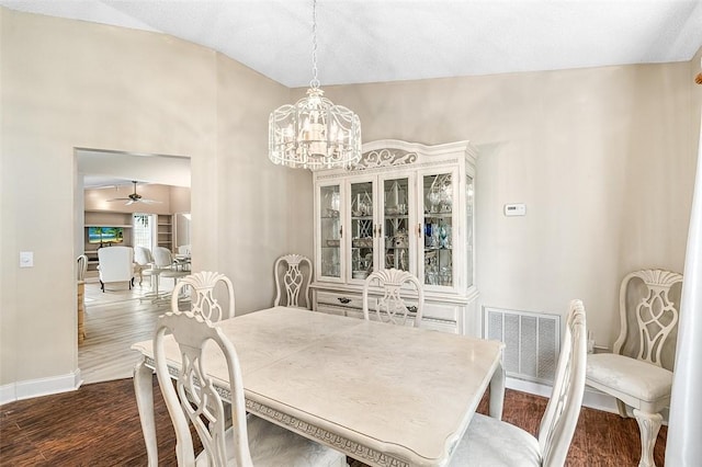 dining room with dark wood-style floors, baseboards, visible vents, and ceiling fan with notable chandelier