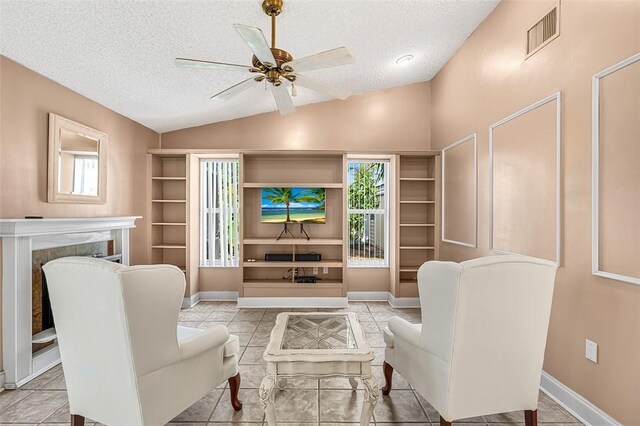 living area featuring a wealth of natural light, visible vents, vaulted ceiling, and a textured ceiling