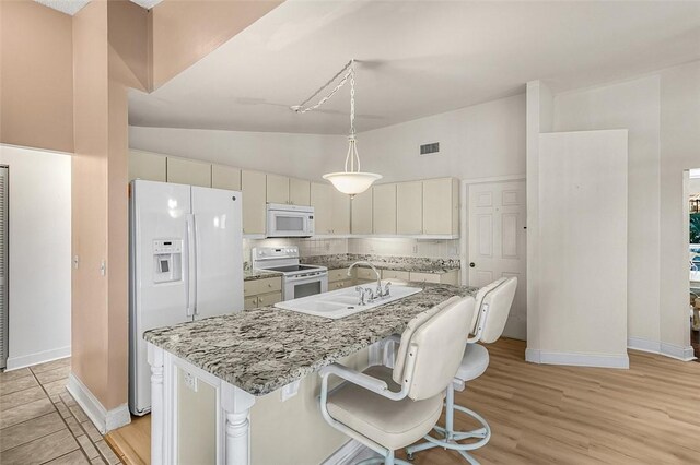 kitchen with white appliances, tasteful backsplash, light wood-style floors, and a sink