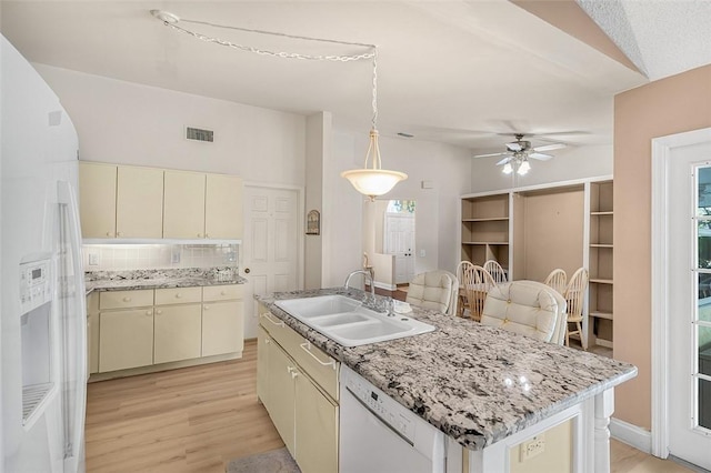 kitchen with white appliances, cream cabinets, a sink, and visible vents