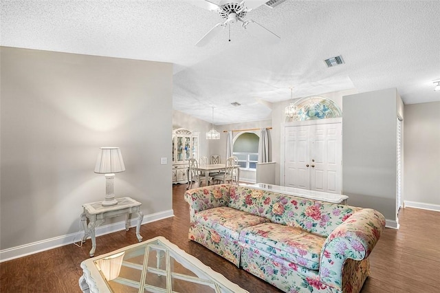 living area featuring baseboards, wood finished floors, visible vents, and a ceiling fan