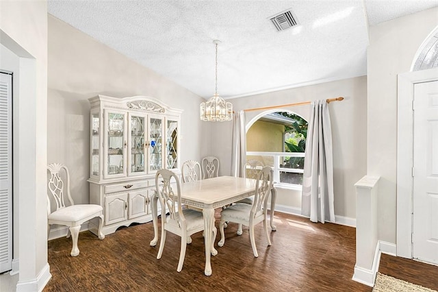 dining area with dark wood-style flooring, visible vents, an inviting chandelier, a textured ceiling, and baseboards