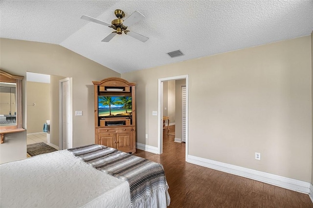 bedroom featuring dark wood finished floors, lofted ceiling, visible vents, a textured ceiling, and baseboards