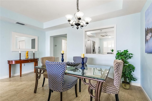 5520 N Harbor Village Dr Unit 204, Vero Beach, FL 32967 - dining area with wood finished floors, a chandelier, a tray ceiling, and baseboards
