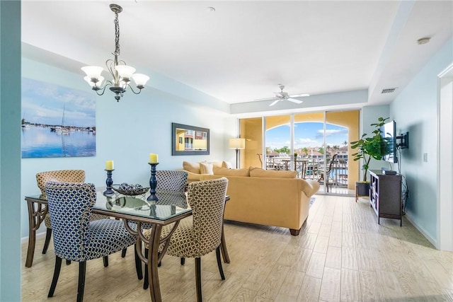 5520 N Harbor Village Dr Unit 204, Vero Beach, FL 32967 - dining space with light wood-type flooring, ceiling fan, a chandelier, baseboards, and a raised ceiling