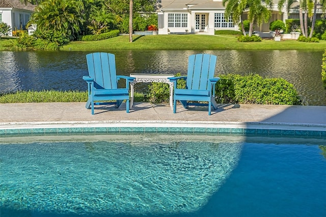 view of pool featuring a lawn, a water view, and a patio area