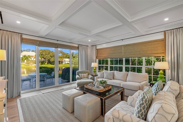 sunroom with beam ceiling, a water view, and coffered ceiling