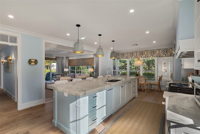 kitchen featuring white cabinets, sink, a kitchen island with sink, and decorative light fixtures