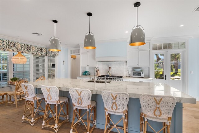 kitchen with a large island, a kitchen breakfast bar, sink, and decorative light fixtures