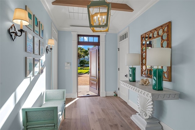 entryway featuring a chandelier, hardwood / wood-style flooring, and crown molding