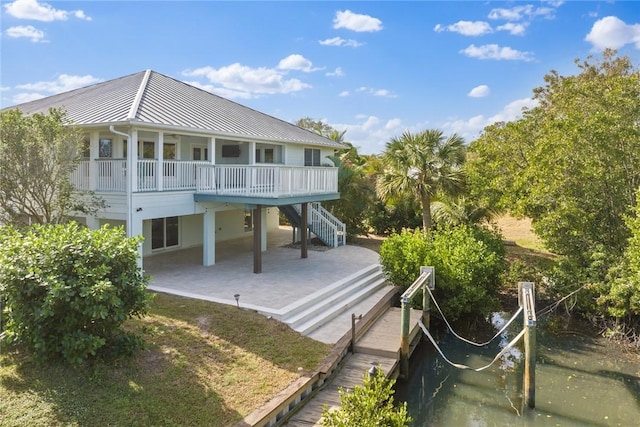 5440 95th St, Sebastian, FL 32958 - back of property with a metal roof, a standing seam roof, stairs, and a patio area