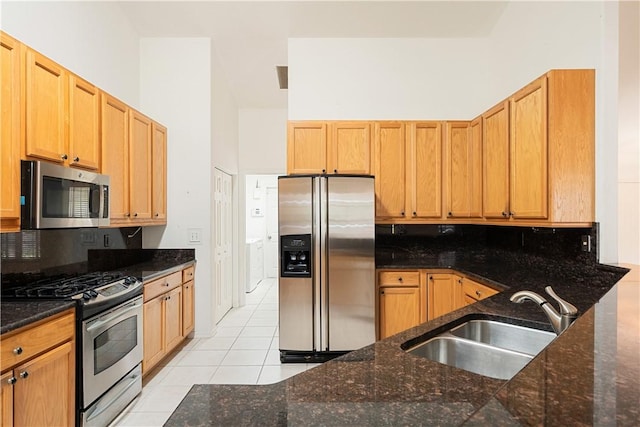 kitchen with light tile patterned floors, a high ceiling, a sink, appliances with stainless steel finishes, and decorative backsplash