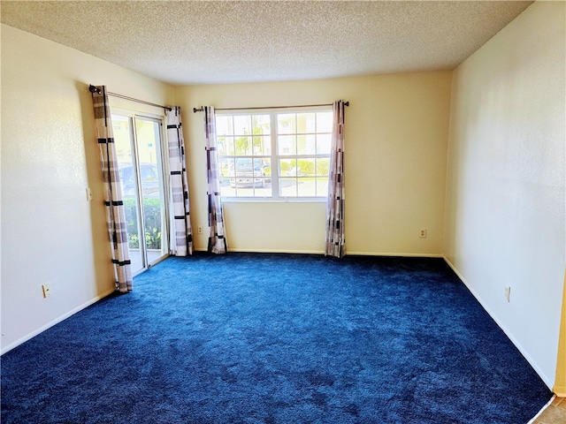 unfurnished room featuring a textured ceiling and dark carpet