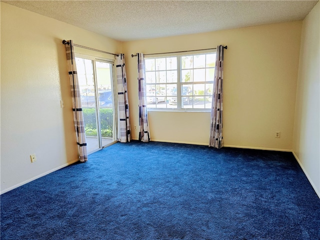 empty room with a textured ceiling and dark carpet