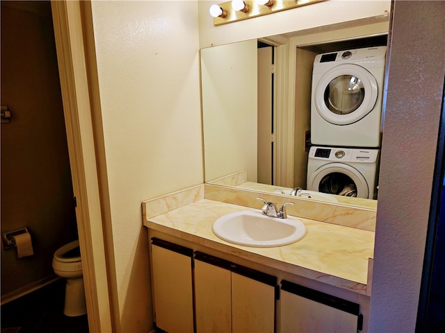 bathroom featuring stacked washer and dryer, vanity, and toilet