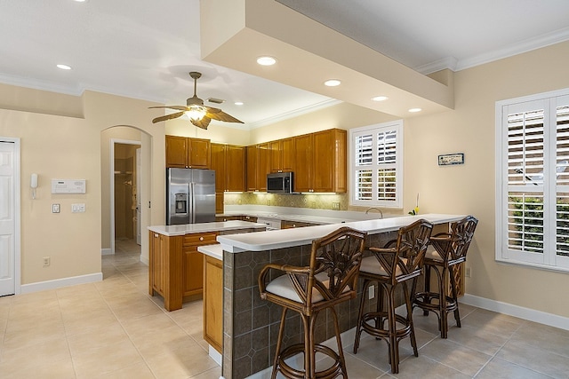 kitchen featuring a kitchen breakfast bar, a wealth of natural light, kitchen peninsula, and appliances with stainless steel finishes