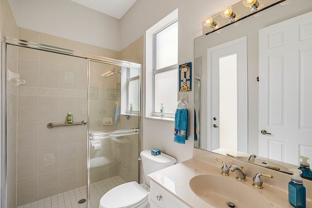 bathroom featuring toilet, vanity, and a shower with shower door