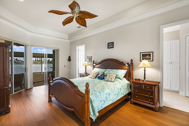 bedroom featuring access to outside, ornamental molding, hardwood / wood-style floors, a water view, and ceiling fan