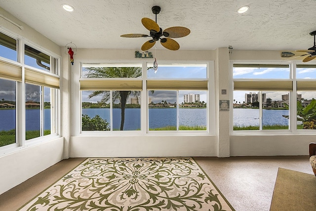 unfurnished sunroom featuring a water view and ceiling fan