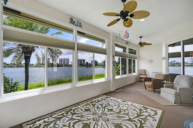 sunroom / solarium with ceiling fan, a water view, and a healthy amount of sunlight