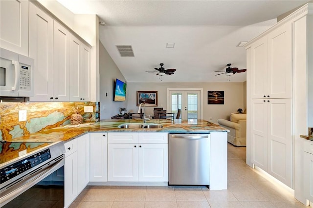 kitchen featuring appliances with stainless steel finishes, sink, light tile patterned floors, white cabinetry, and kitchen peninsula