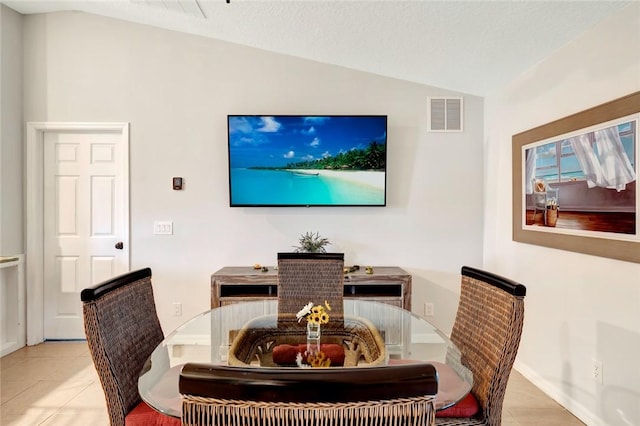 dining space featuring light tile patterned flooring, a textured ceiling, and lofted ceiling