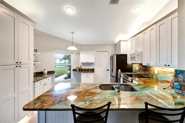 kitchen featuring appliances with stainless steel finishes, sink, a kitchen bar, and kitchen peninsula