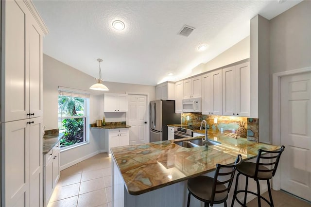 kitchen with a kitchen breakfast bar, kitchen peninsula, vaulted ceiling, and stainless steel appliances