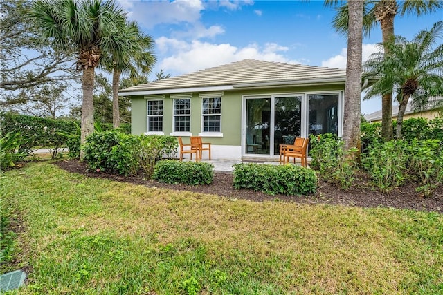 back of property with a yard and a patio area