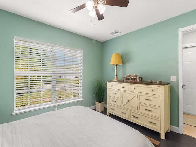 bedroom with visible vents, baseboards, ceiling fan, and dark wood-style flooring