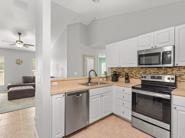 kitchen featuring visible vents, a sink, appliances with stainless steel finishes, light countertops, and vaulted ceiling