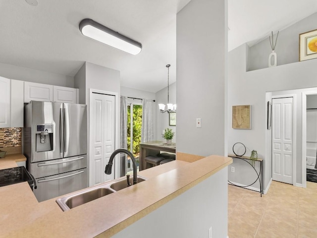 kitchen featuring light tile patterned floors, stainless steel fridge with ice dispenser, a sink, decorative backsplash, and light countertops