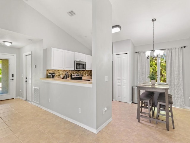 kitchen with stainless steel appliances, visible vents, white cabinets, and vaulted ceiling