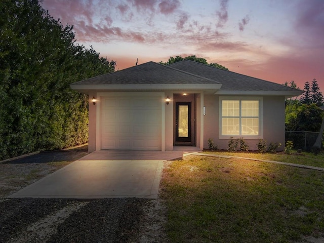 view of front of property featuring stucco siding, a yard, an attached garage, and a shingled roof