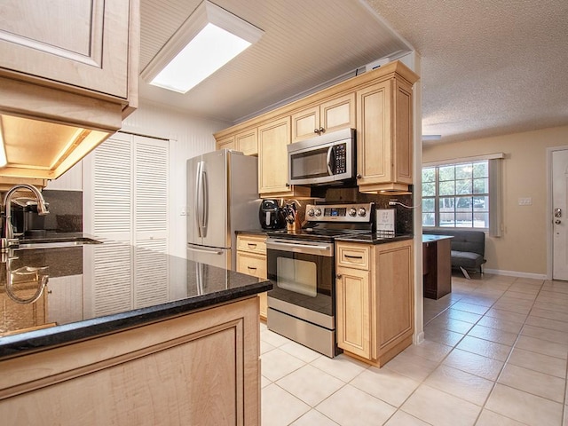 kitchen featuring light brown cabinets, a sink, light tile patterned flooring, and appliances with stainless steel finishes