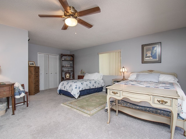 carpeted bedroom featuring a ceiling fan, a closet, and a textured ceiling