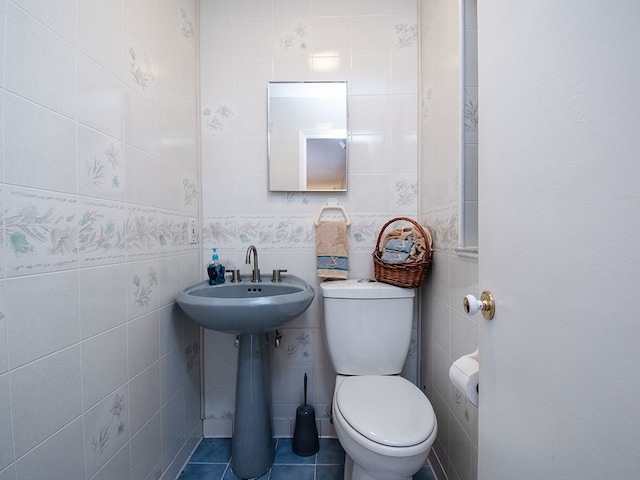 half bath with tile walls, toilet, and tile patterned floors