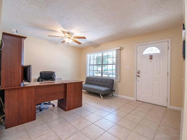 home office featuring a textured ceiling, ceiling fan, baseboards, and light tile patterned floors