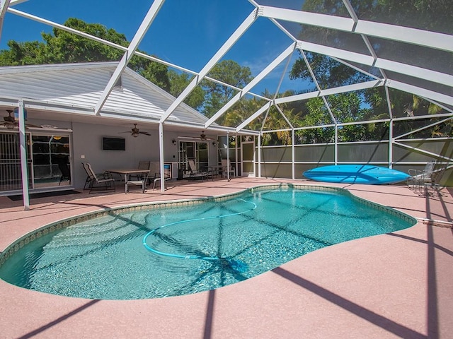 view of swimming pool with fence, glass enclosure, a fenced in pool, a ceiling fan, and a patio area