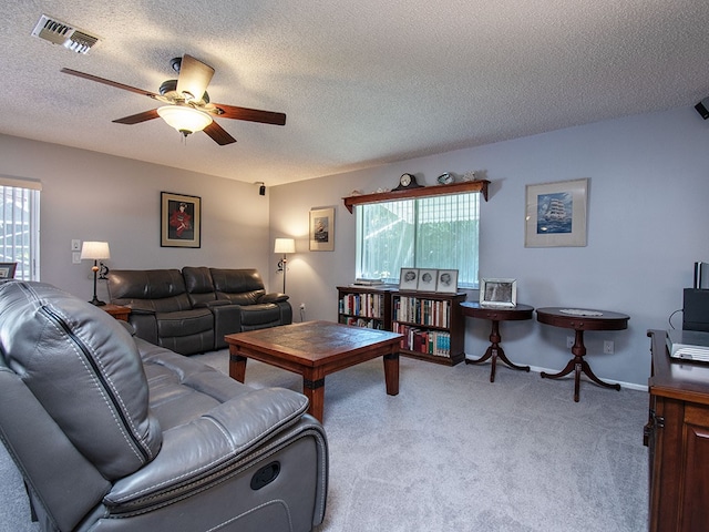 carpeted living room with baseboards, visible vents, ceiling fan, and a textured ceiling