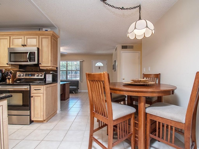 dining area featuring a textured ceiling, visible vents, and light tile patterned floors