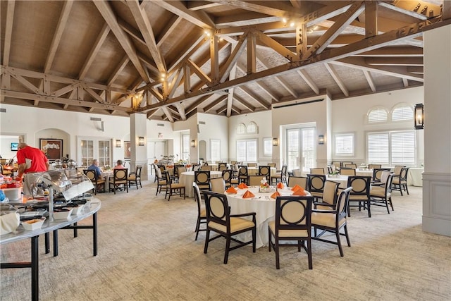 carpeted dining room featuring high vaulted ceiling and beamed ceiling