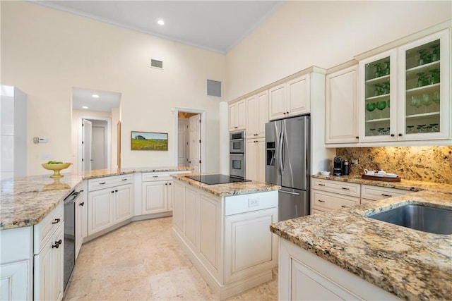 kitchen with ornamental molding, appliances with stainless steel finishes, a center island, and light stone countertops