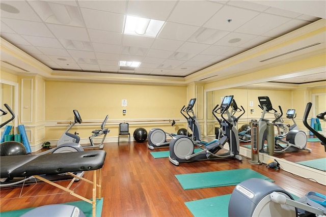 gym with crown molding, a paneled ceiling, a tray ceiling, and hardwood / wood-style floors