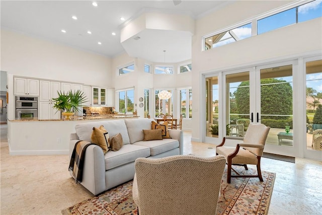 living room with a towering ceiling, ornamental molding, and french doors