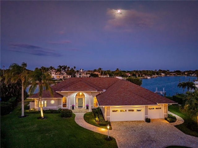 mediterranean / spanish-style home featuring a garage, a water view, and a yard