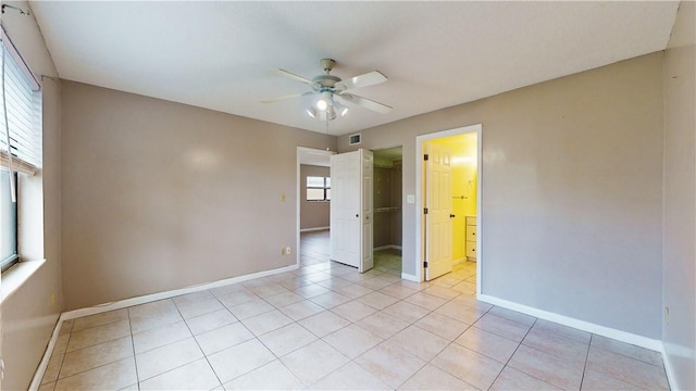 tiled spare room featuring a wealth of natural light and ceiling fan