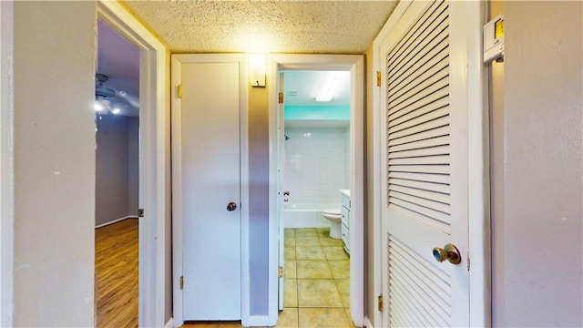 corridor featuring light tile patterned floors and a textured ceiling