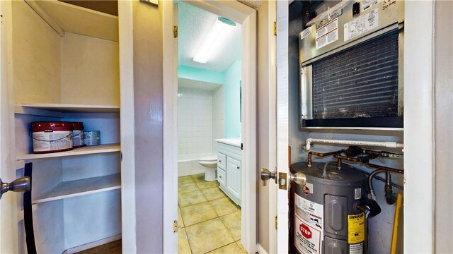 bathroom with tile patterned flooring, electric water heater, and toilet